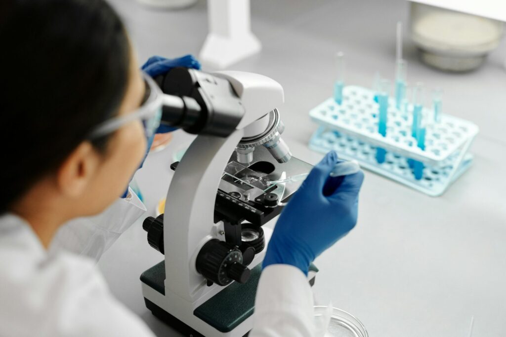 Scientist conducting research in a lab using a microscope and dropper.